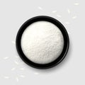 Rice flour in a black bowl with scattered white grains on gray background. Top view Royalty Free Stock Photo